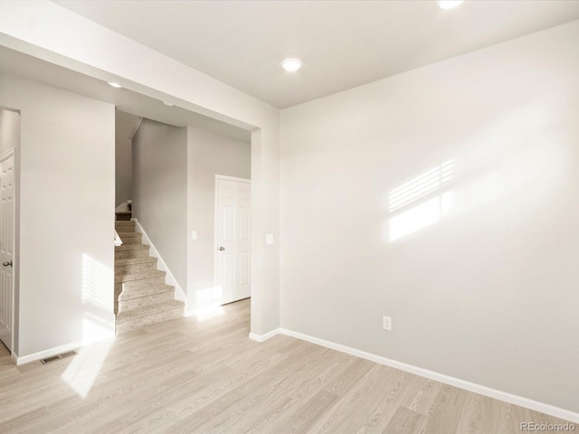 empty room with visible vents, baseboards, stairs, recessed lighting, and light wood-style flooring