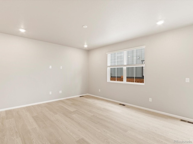 empty room featuring visible vents, baseboards, and light wood finished floors