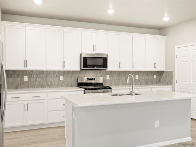 kitchen with a sink, stainless steel appliances, light countertops, white cabinetry, and backsplash