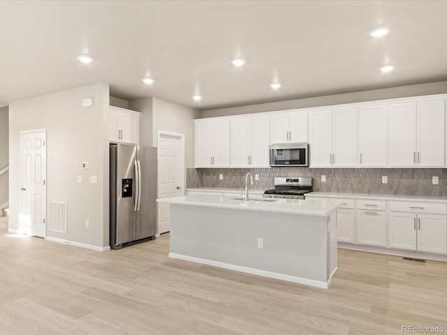 kitchen with decorative backsplash, visible vents, appliances with stainless steel finishes, and a sink