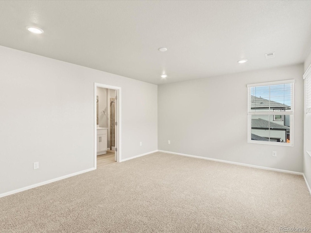 spare room featuring recessed lighting, baseboards, and light colored carpet