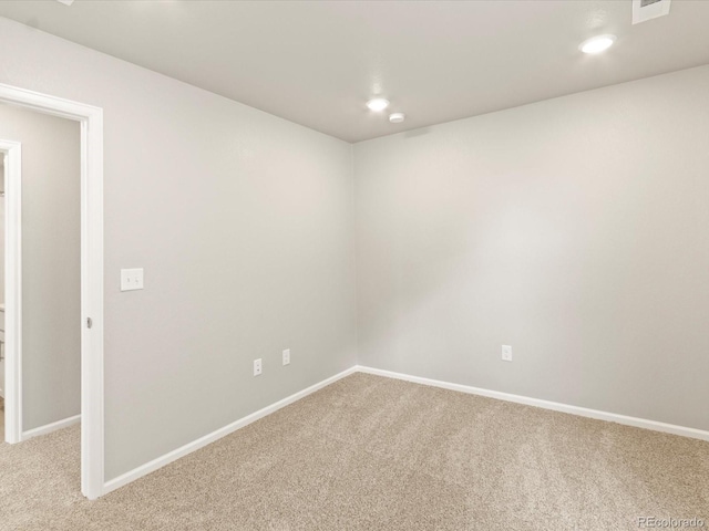 spare room featuring light carpet, recessed lighting, and baseboards