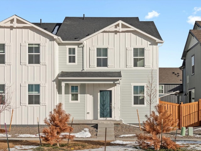 view of front of house featuring fence, board and batten siding, and roof with shingles