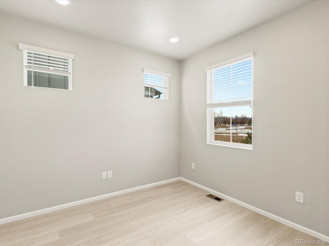 unfurnished room featuring visible vents, a healthy amount of sunlight, light wood-style flooring, and baseboards