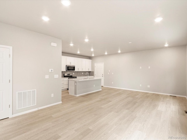 unfurnished living room with a sink, visible vents, recessed lighting, and light wood finished floors