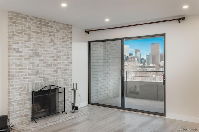 800 N Pearl St Unit 611, Denver, CO 80203 - unfurnished living room with wood finished floors, a view of skyline, baseboards, recessed lighting, and a brick fireplace