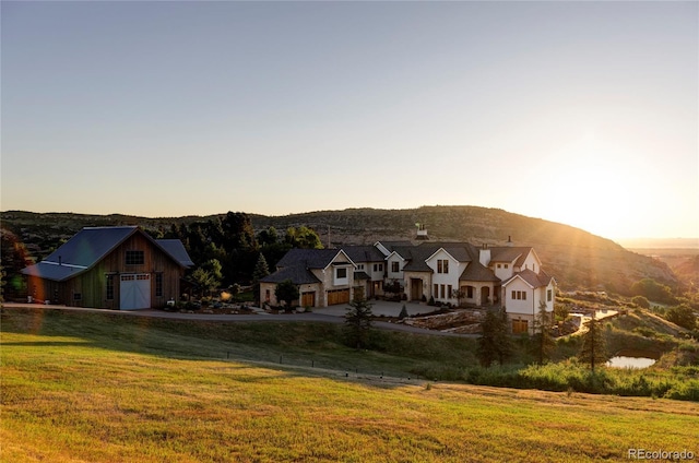 back house at dusk featuring a lawn and a mountain view