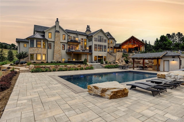 pool at dusk with a gazebo and a patio area