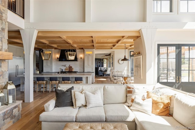 living room with hardwood / wood-style flooring, a chandelier, french doors, coffered ceiling, and sink