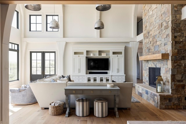 living room featuring a high ceiling, a fireplace, and light hardwood / wood-style floors