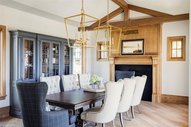 dining space with light wood-type flooring, lofted ceiling with beams, and a chandelier