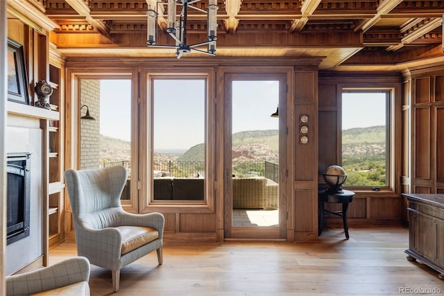 doorway with ornamental molding, a mountain view, a brick fireplace, wood walls, and wood ceiling