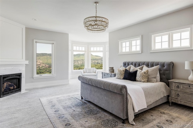 bedroom featuring an inviting chandelier, a high end fireplace, and carpet