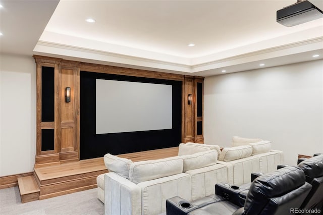 cinema with a raised ceiling, crown molding, and light colored carpet