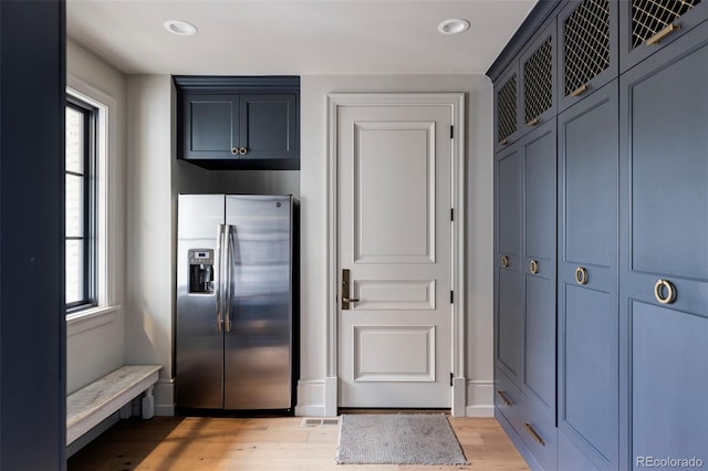 kitchen with stainless steel refrigerator with ice dispenser, blue cabinetry, and light wood-type flooring