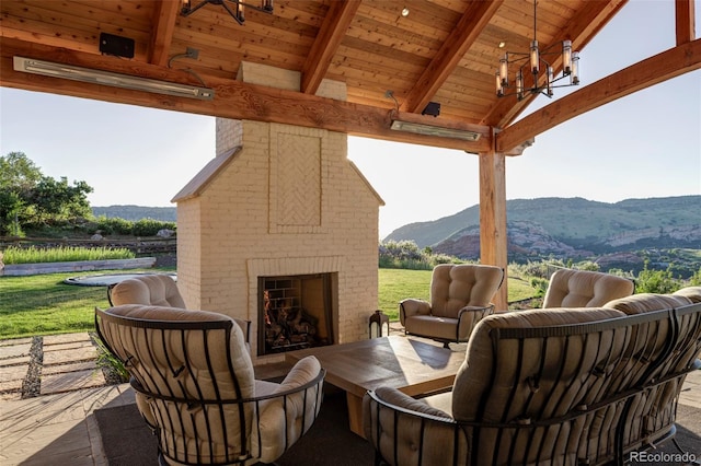 view of patio / terrace featuring an outdoor brick fireplace and a mountain view