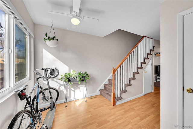 entryway with stairs, baseboards, wood finished floors, and a healthy amount of sunlight