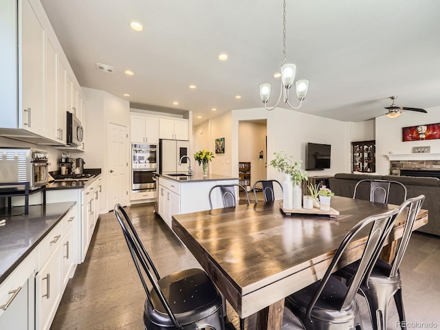3508 E 140th Pl, Thornton, CO 80602 - dining area featuring a chandelier, recessed lighting, ceiling fan, dark wood-type flooring, and a stone fireplace