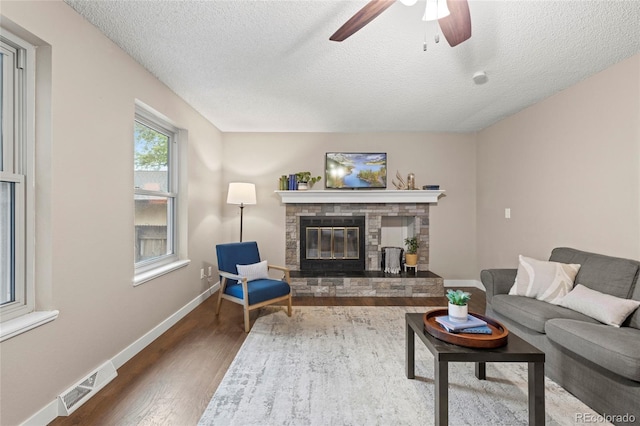 1285 Aberdeen Dr, Broomfield, CO 80020 - living area with a stone fireplace, baseboards, wood finished floors, a textured ceiling, and ceiling fan