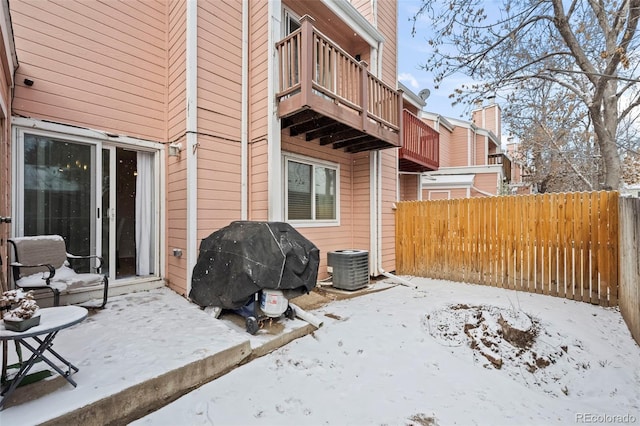 snow covered patio featuring a balcony, cooling unit, and grilling area