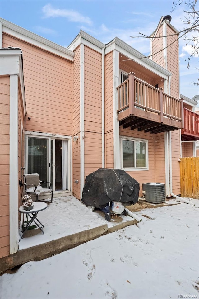 snow covered back of property featuring cooling unit and a balcony