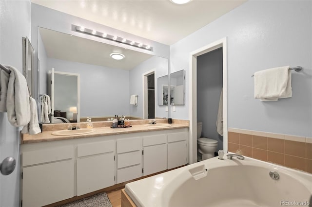 bathroom with vanity, a bath, and toilet