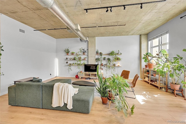 living room featuring visible vents, baseboards, wood finished floors, and track lighting