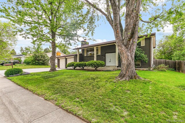 7503 Saulsbury St, Arvada, CO 80003 - view of front of home featuring concrete driveway, a chimney, and a garage