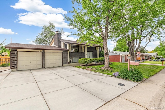 7503 Saulsbury St, Arvada, CO 80003 - view of front of property featuring concrete driveway, brick siding, a garage, and a chimney