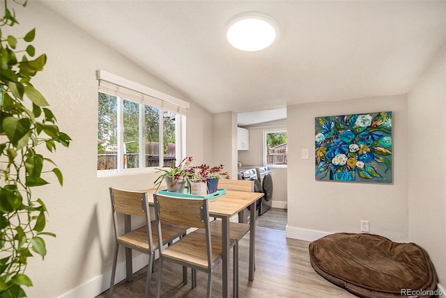 dining room featuring vaulted ceiling, hardwood / wood-style floors, and washing machine and clothes dryer