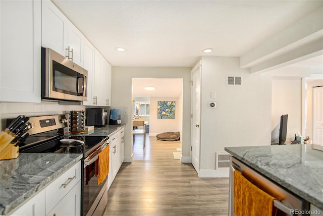 kitchen featuring white cabinets, appliances with stainless steel finishes, and light stone countertops