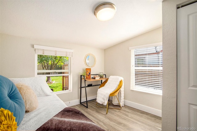 bedroom with light hardwood / wood-style flooring, multiple windows, and lofted ceiling