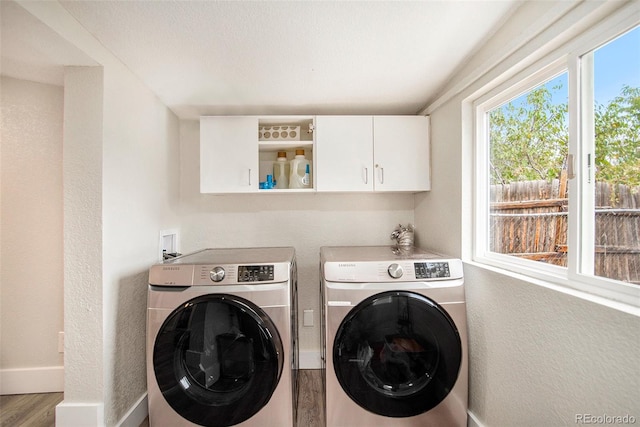 laundry room featuring hardwood / wood-style flooring, separate washer and dryer, and cabinets