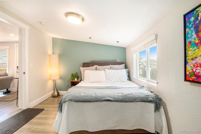 bedroom featuring light hardwood / wood-style floors and lofted ceiling