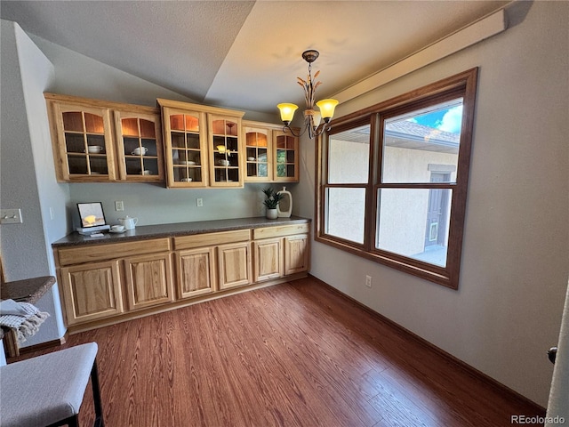 100 River Run Dr, Buena Vista, CO 81211 - kitchen with dark wood-type flooring, a chandelier, dark countertops, vaulted ceiling, and glass insert cabinets