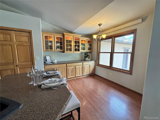 100 River Run Dr, Buena Vista, CO 81211 - kitchen with dark countertops, vaulted ceiling, light wood-style flooring, a chandelier, and glass insert cabinets