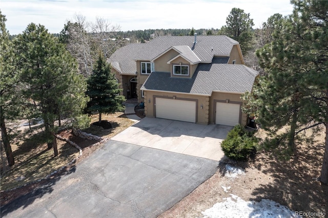 view of front of house featuring an attached garage, a shingled roof, driveway, and stucco siding
