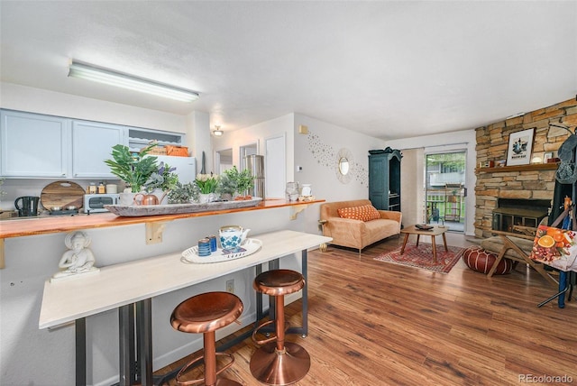 kitchen featuring a breakfast bar, wood finished floors, open floor plan, and a fireplace