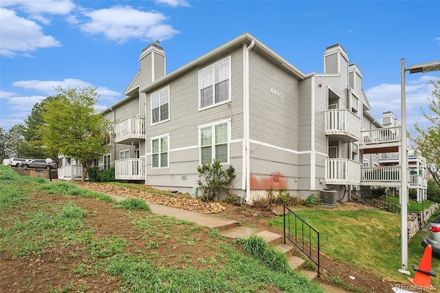 back of property featuring a chimney, central AC, and a balcony