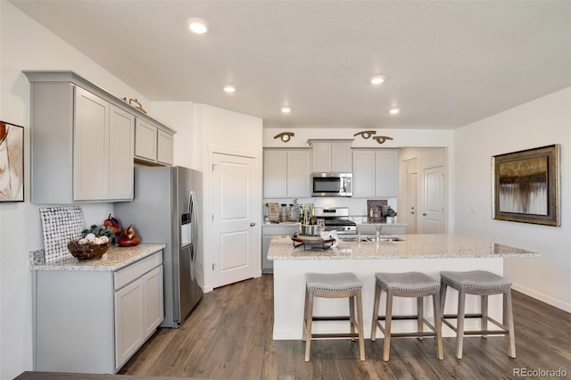 kitchen with gray cabinetry, an island with sink, stainless steel appliances, and dark hardwood / wood-style floors