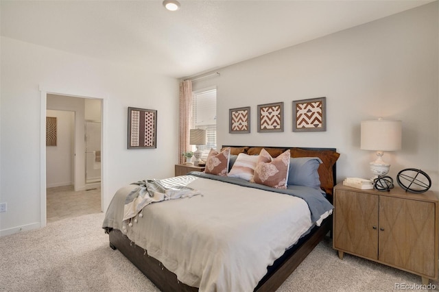 bedroom with ensuite bath and light colored carpet