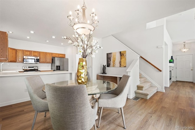 10681 Cherrybrook Cir, Highlands Ranch, CO 80126 - dining area featuring a chandelier, stairs, recessed lighting, light wood-style flooring, and baseboards