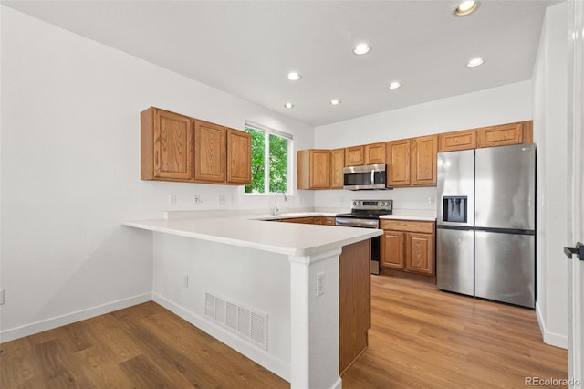 10681 Cherrybrook Cir, Highlands Ranch, CO 80126 - kitchen featuring appliances with stainless steel finishes, a peninsula, recessed lighting, light wood-style flooring, and light countertops