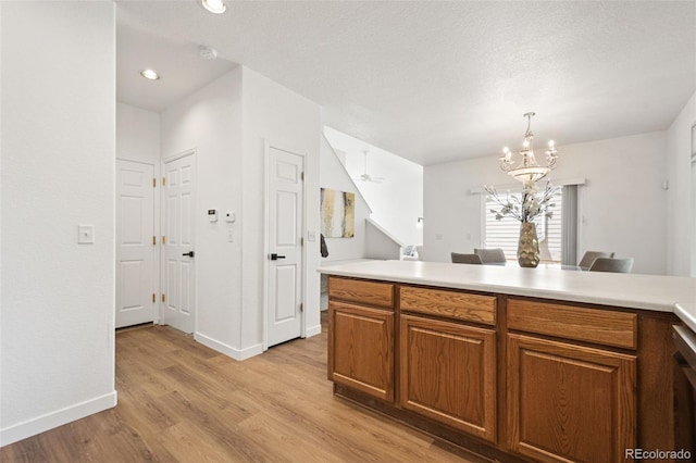 10681 Cherrybrook Cir, Highlands Ranch, CO 80126 - kitchen featuring light wood finished floors, brown cabinets, light countertops, a chandelier, and baseboards