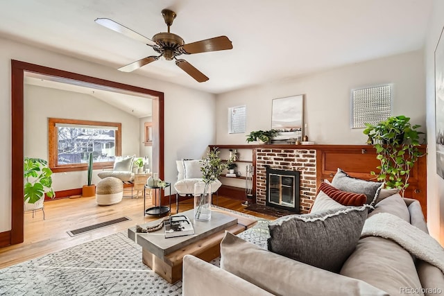 living room featuring ceiling fan, hardwood / wood-style floors, vaulted ceiling, and a fireplace