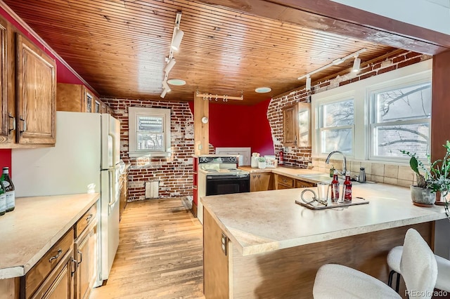 kitchen with wooden ceiling, rail lighting, a kitchen breakfast bar, sink, and kitchen peninsula