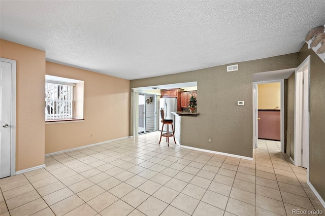 spare room with light tile patterned floors and a textured ceiling