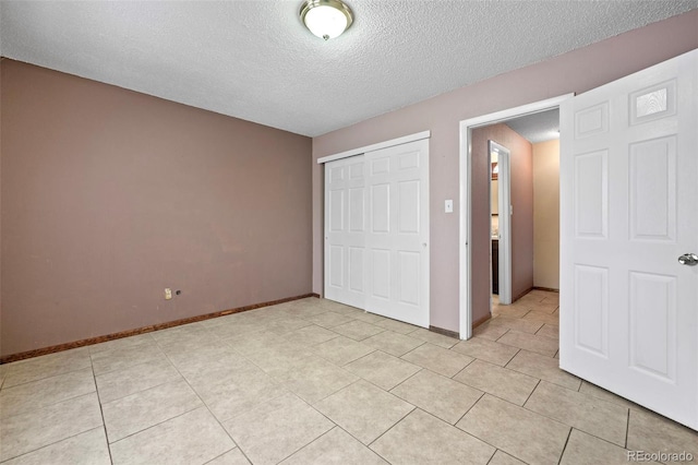 unfurnished bedroom with light tile patterned flooring, a textured ceiling, and a closet