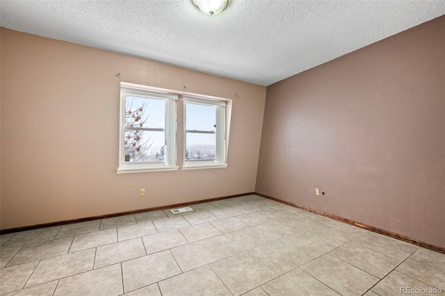 unfurnished room featuring light tile patterned flooring and a textured ceiling