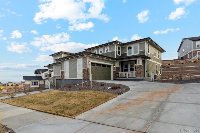 prairie-style home with driveway, stone siding, a garage, and a front yard